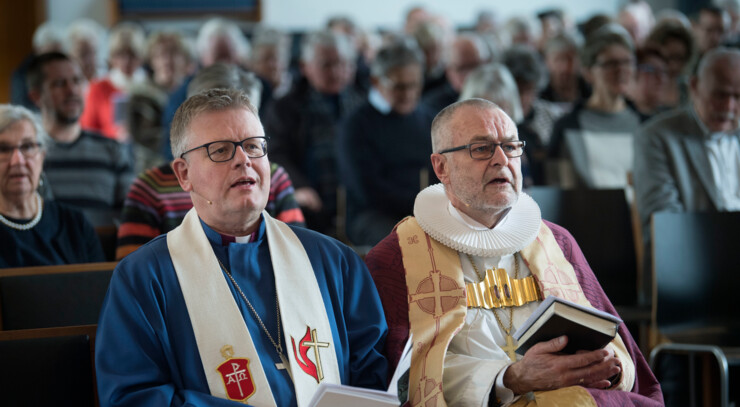 Christian Alsted (Biskop i Metodistkirken) og Henning Toft Bro (Biskop i Aalborg Stift) sidder på kirkebænk sammen og synger.